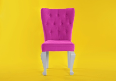 Photo of Stylish pink chair on yellow background. Element of interior design