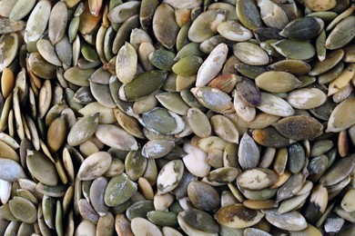 Many peeled pumpkin seeds as background, top view