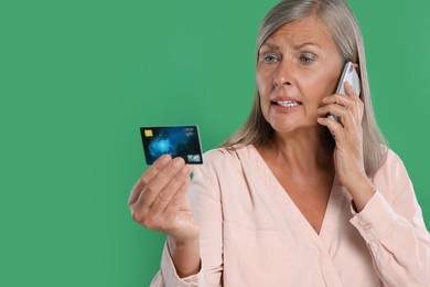 Photo of Worried woman with credit card talking on smartphone against green background, space for text. Be careful - fraud
