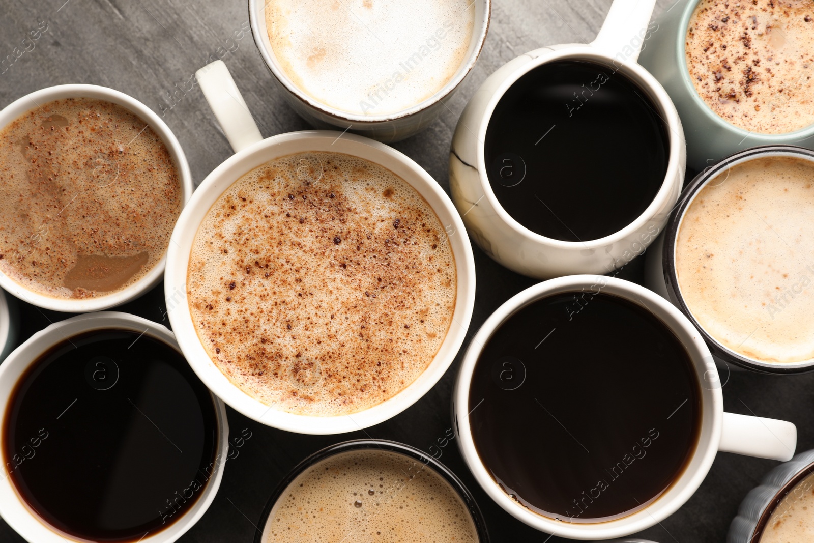 Photo of Many cups of different coffees on slate table, flat lay