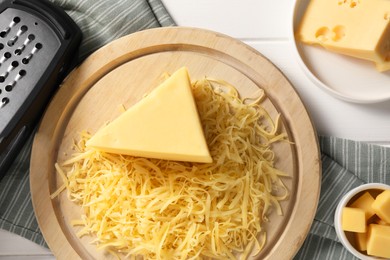 Grated and whole pieces of cheese on white wooden table, flat lay