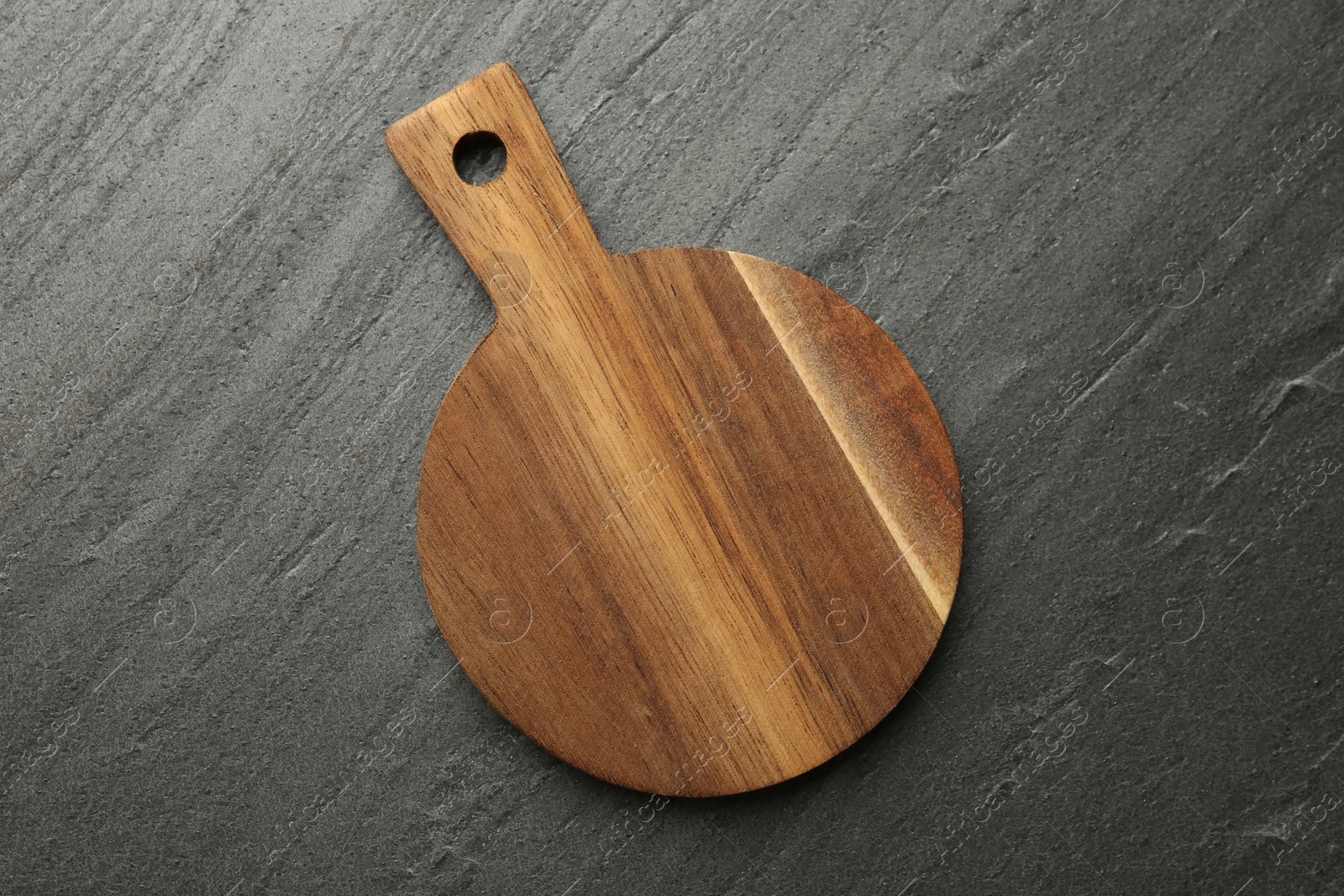 Photo of One wooden cutting board on dark grey table, top view