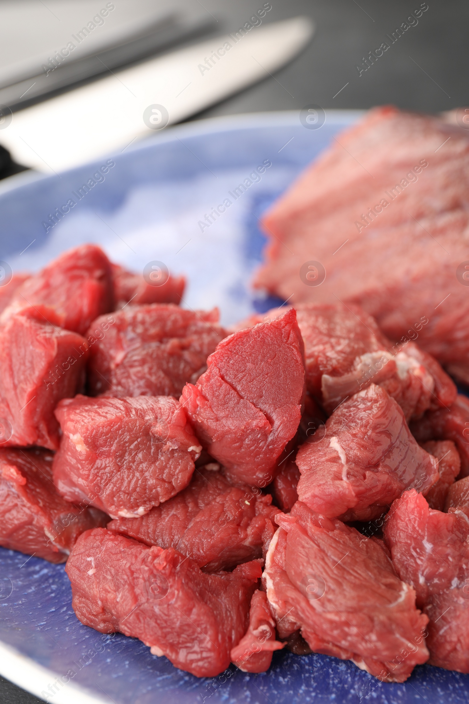 Photo of Plate with pieces of raw beef meat on table, closeup