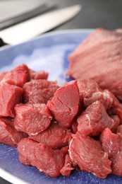 Photo of Plate with pieces of raw beef meat on table, closeup