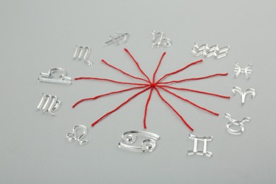 Photo of Zodiac compatibility. Signs and red threads on grey background