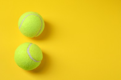 Photo of Two tennis balls on yellow background, above view. Space for text