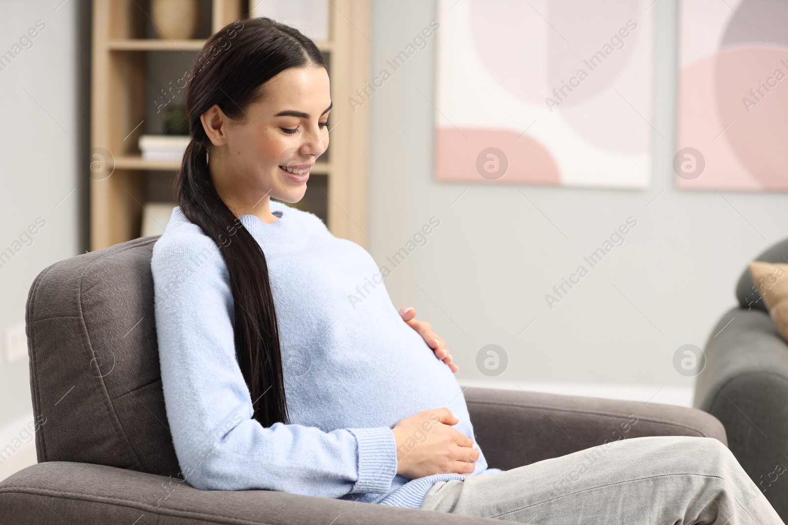 Photo of Happy pregnant woman on armchair at home