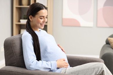 Happy pregnant woman on armchair at home