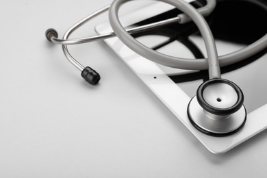 Photo of Medical stethoscope and tablet on white background, closeup. Space for text