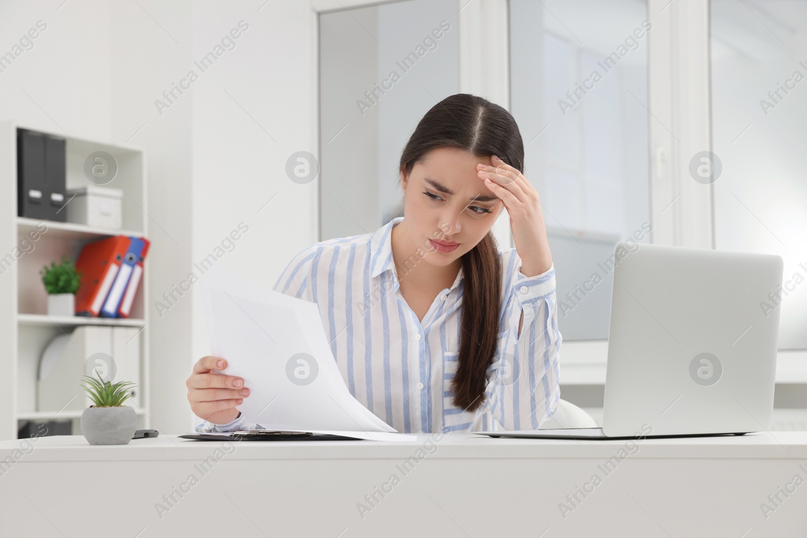 Photo of Unhappy young female intern at table in office