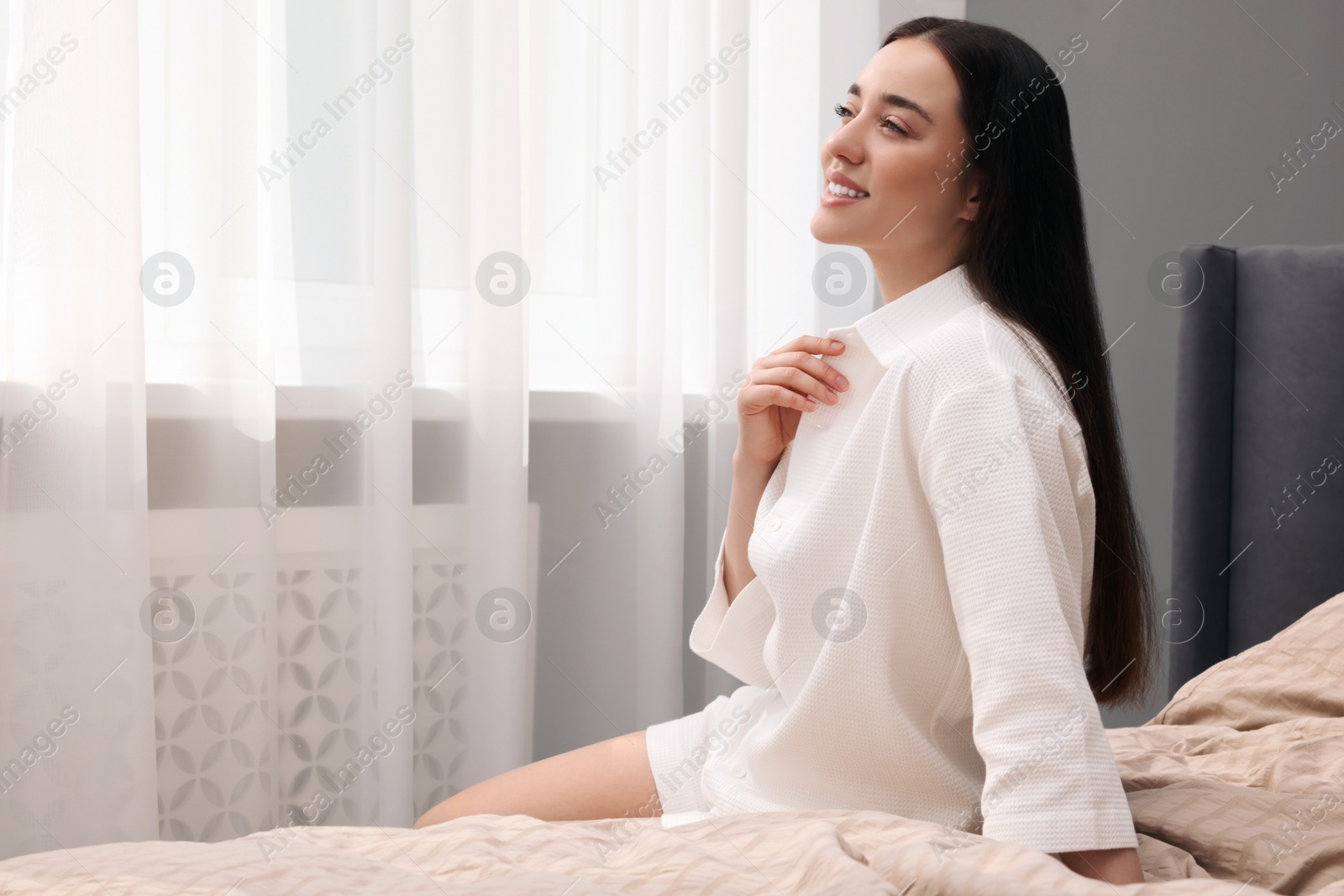 Photo of Beautiful woman sitting on bed at home, space for text. Lazy morning