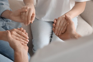 Group of religious people holding hands and praying together indoors, closeup