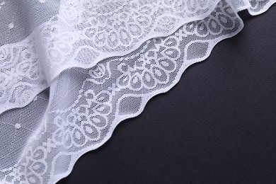 Photo of White lace on black background, top view. Space for text