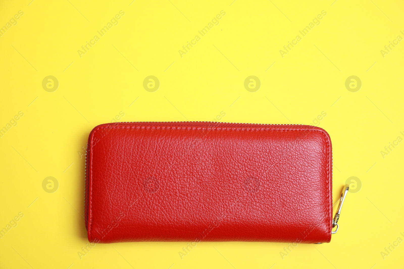 Photo of Stylish red leather purse on yellow background, top view