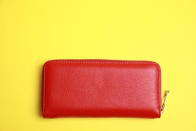 Photo of Stylish red leather purse on yellow background, top view