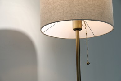 Photo of Stylish lamp near light wall, closeup. Space for text