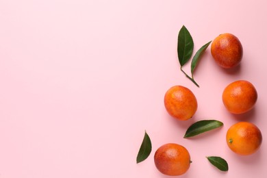 Photo of Many ripe sicilian oranges and leaves on pink background, flat lay. Space for text