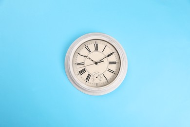 Photo of Stylish vintage wall clock on turquoise background, top view