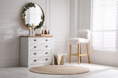 Photo of Modern room interior with chest of drawers and mirror on white wall