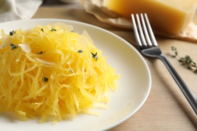 Photo of Plate with cooked spaghetti squash on wooden table, closeup