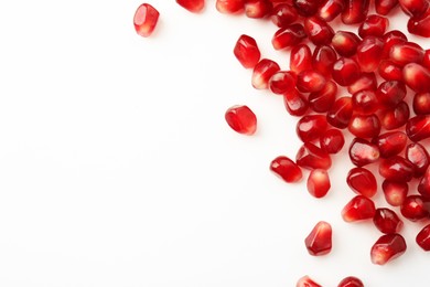 Many ripe juicy pomegranate grains on white background, flat lay. Space for text