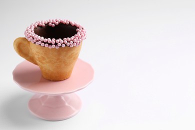 Photo of Delicious edible biscuit cup decorated with sprinkles on white background, space for text