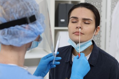 Photo of Laboratory testing. Doctor in uniform taking sample from patient's nose with cotton swab at hospital