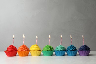 Delicious birthday cupcakes with burning candles on table