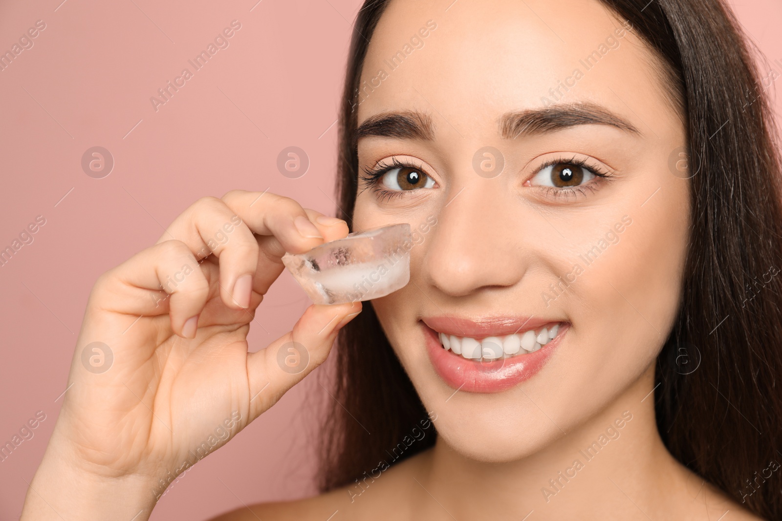 Photo of Young woman with ice cube on color background. Skin care