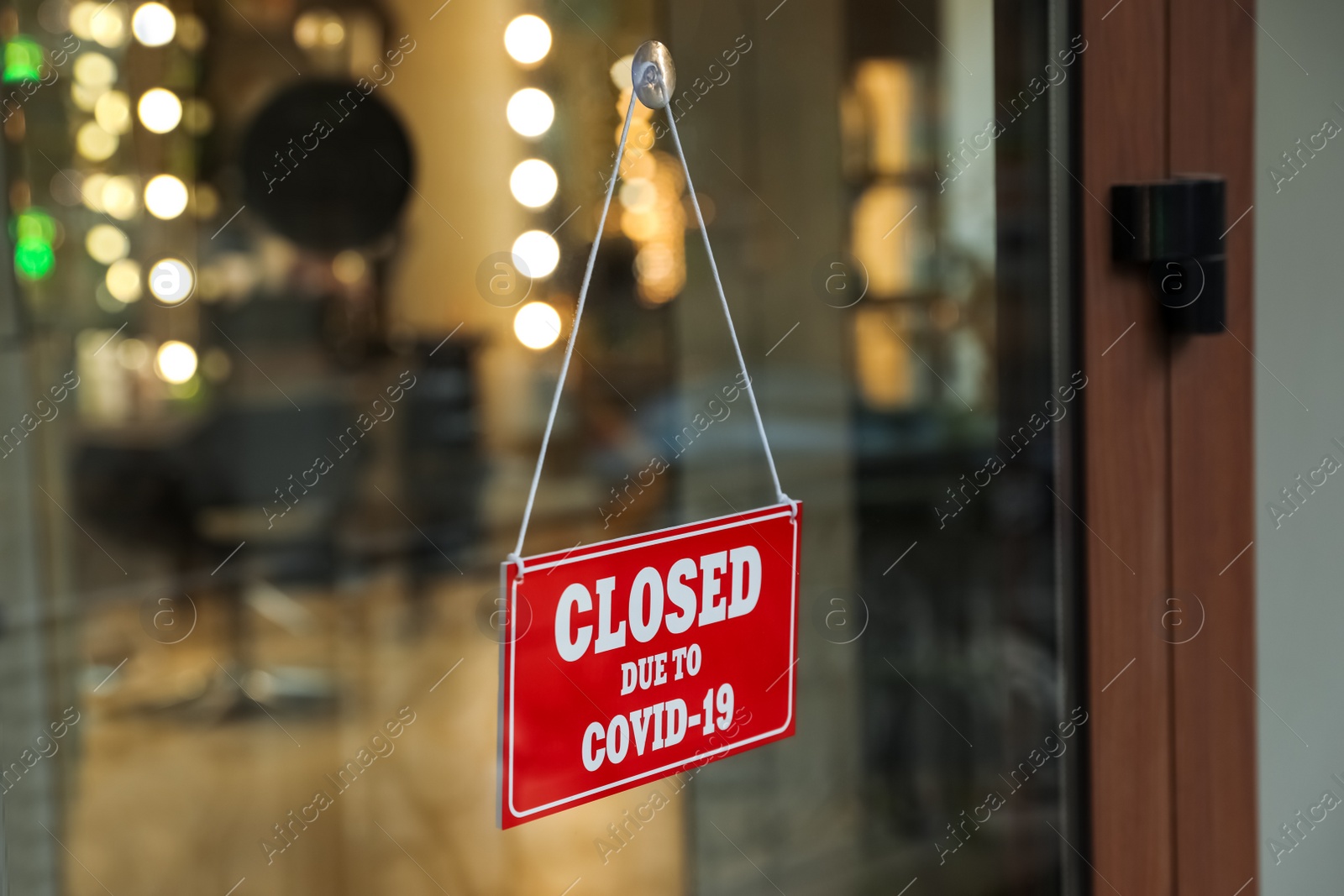 Photo of Red sign with words Closed Due To Covid-19 hanging on glass door