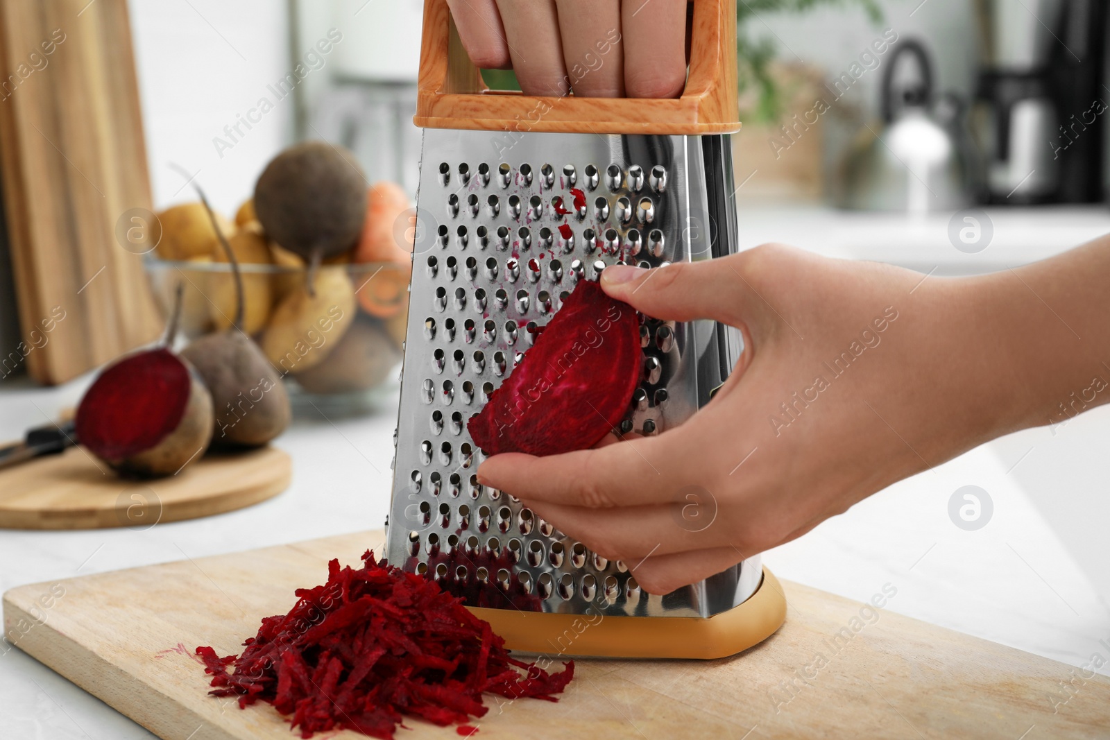 Photo of Woman grating fresh beetroot at kitchen counter, closeup