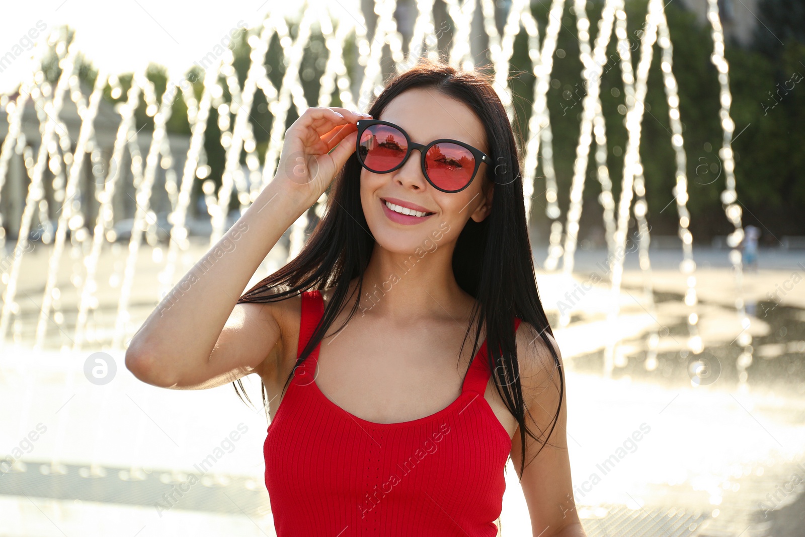 Photo of Beautiful young woman wearing stylish sunglasses outdoors