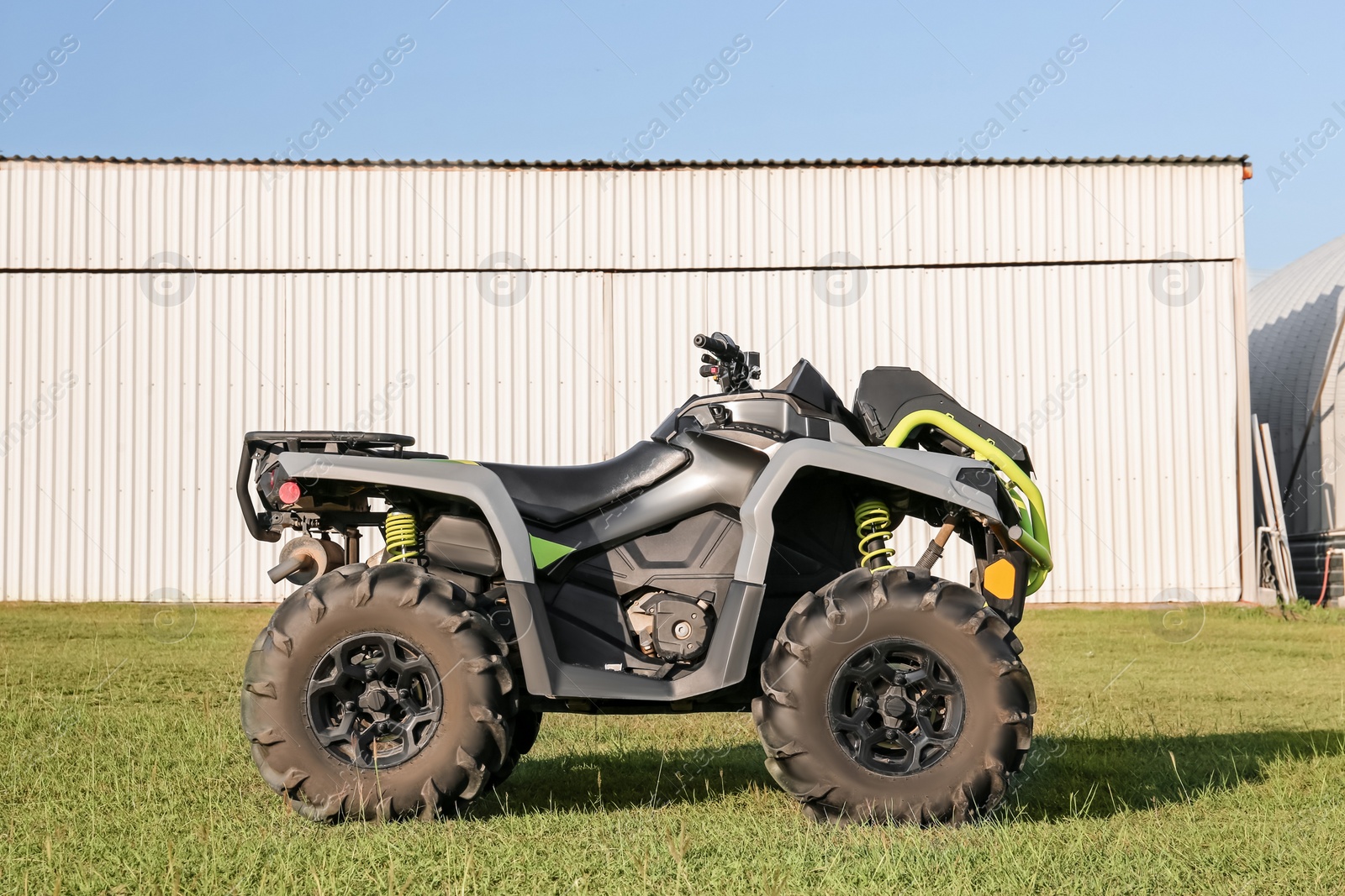 Photo of Modern quad bike in field near hangar on sunny day