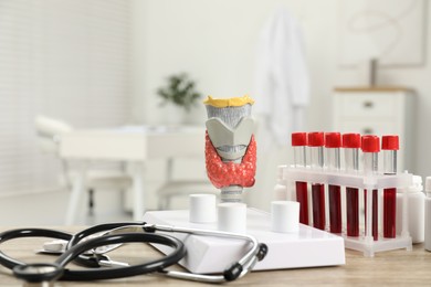 Photo of Endocrinology. Stethoscope, model of thyroid gland and blood samples in test tubes on table indoors