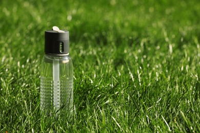 Photo of Sport bottle of water on green grass, space for text