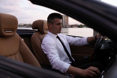 Photo of Stylish handsome businessman driving luxury convertible car