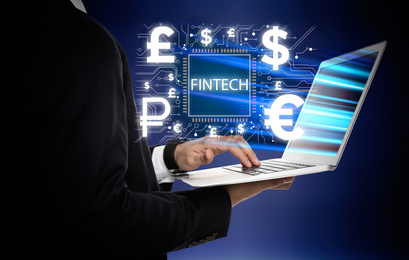 Image of Fintech concept. Man with laptop and digital schema on blue background, closeup