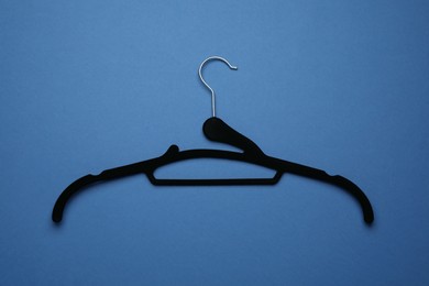 Empty clothes hanger on blue background, top view