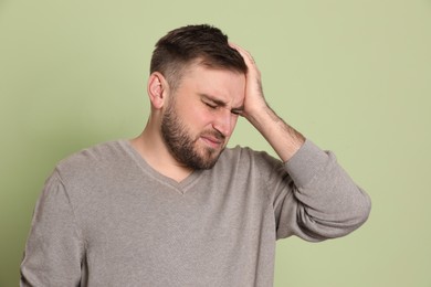 Photo of Man suffering from migraine on light green background