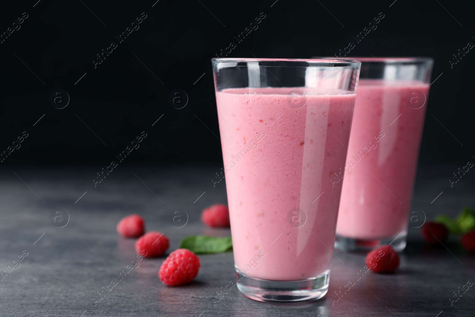 Photo of Delicious smoothie in glasses and fresh raspberries on table