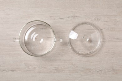 Photo of One empty glass pot and lid on light wooden table. flat lay