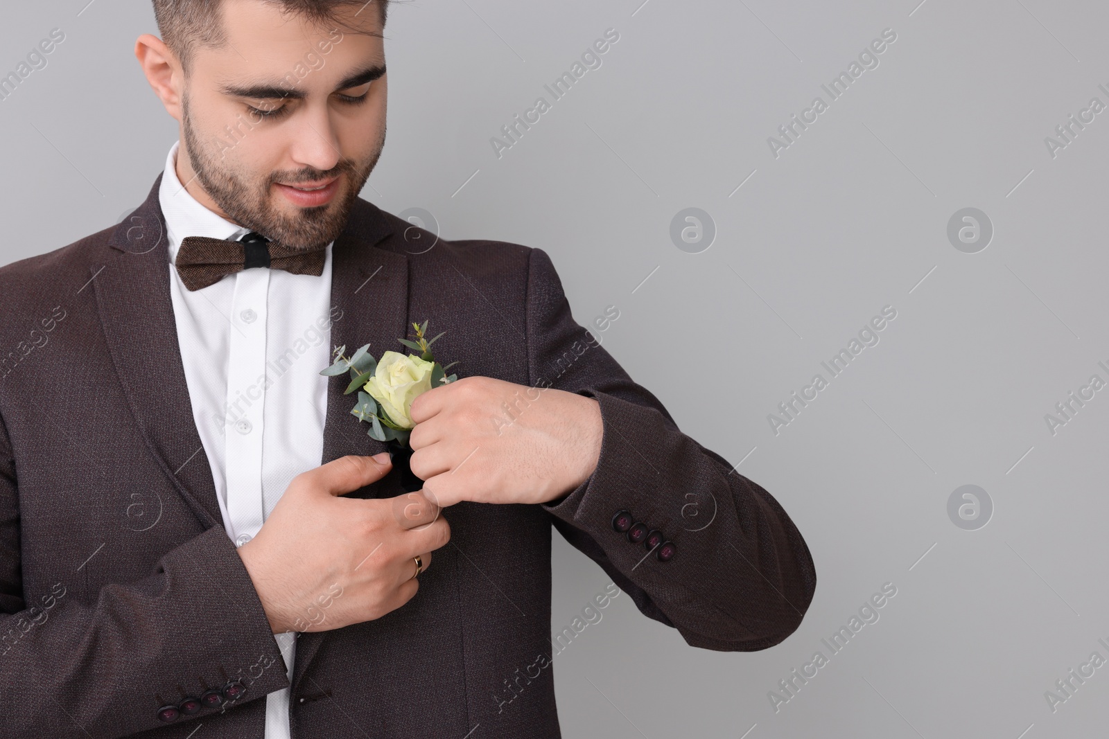 Photo of Groom with boutonniere on light grey background, space for text. Wedding accessory