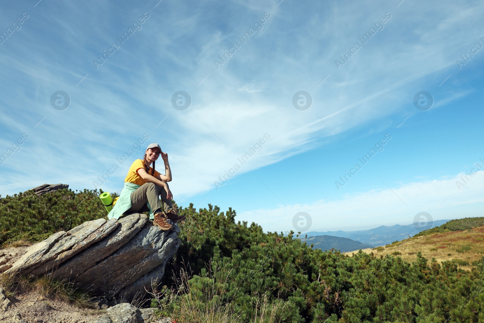 Photo of Tourist with backpack on cliff in mountains. Space for text