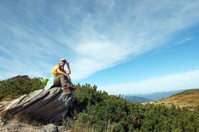 Photo of Tourist with backpack on cliff in mountains. Space for text