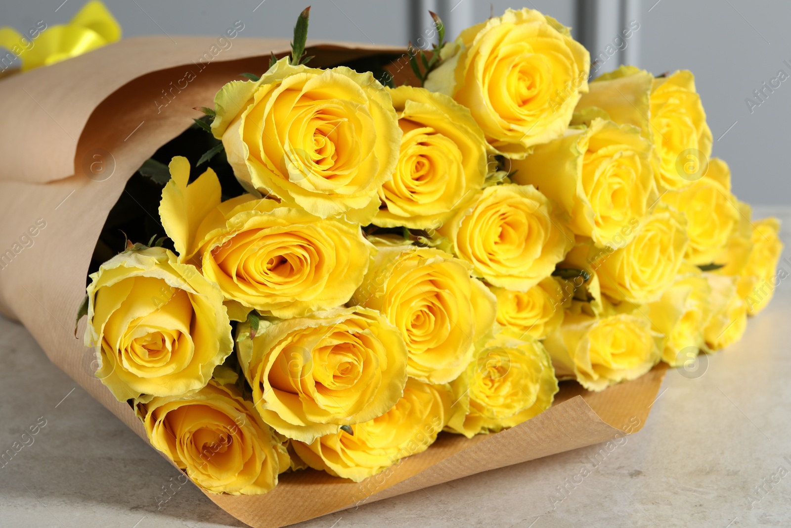 Photo of Beautiful bouquet of yellow roses on light grey table, closeup