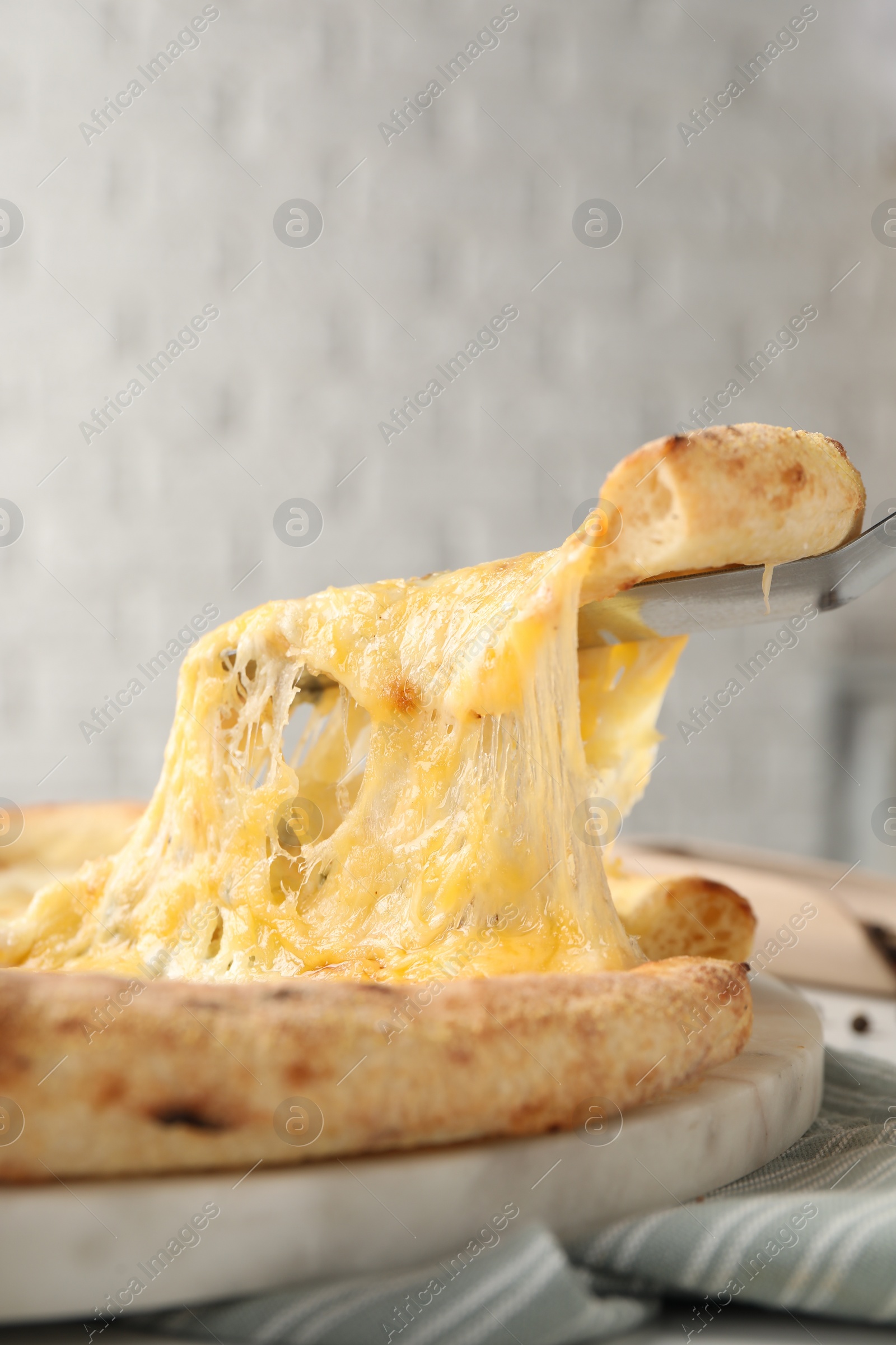 Photo of Taking piece of delicious cheese pizza at table, closeup