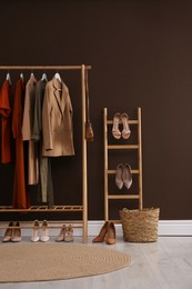 Photo of Modern dressing room interior with clothing rack near brown wall