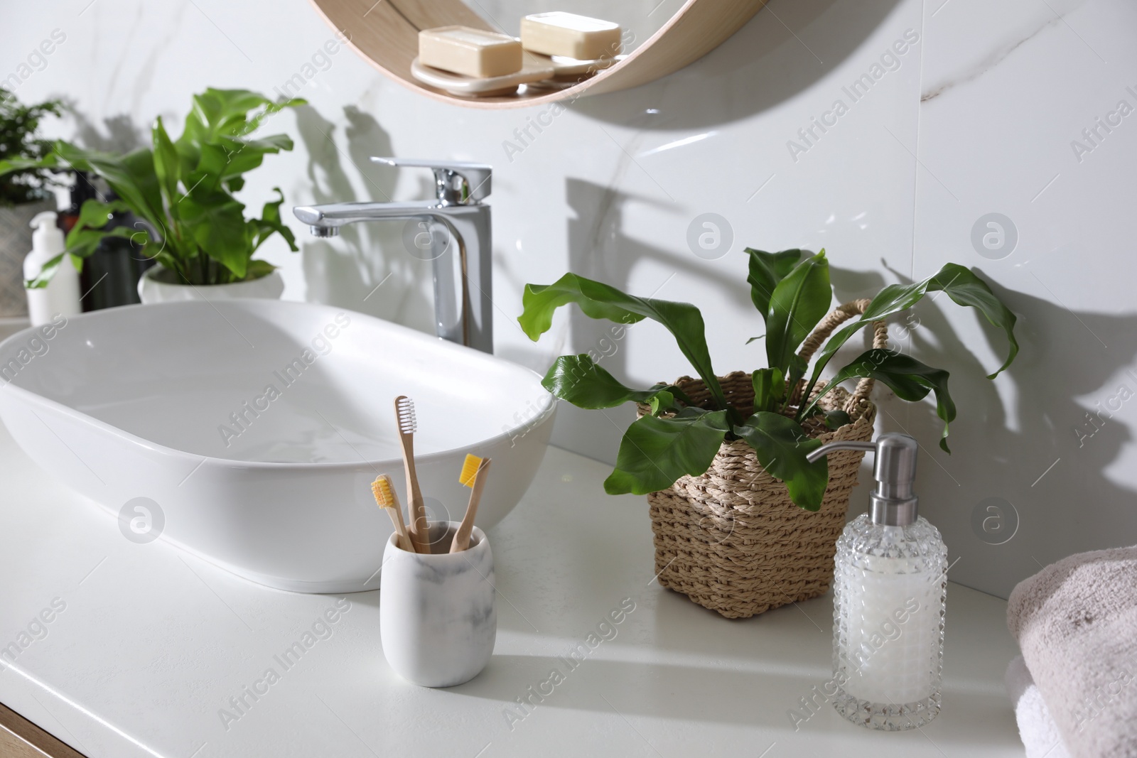 Photo of Beautiful green ferns, towels and toiletries on countertop in bathroom