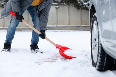 Photo of Man removing snow with shovel near car outdoors, closeup