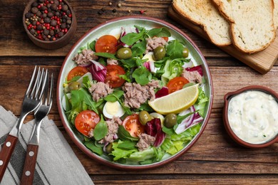 Photo of Plate of delicious salad with canned tuna and vegetables served served on wooden table, flat lay